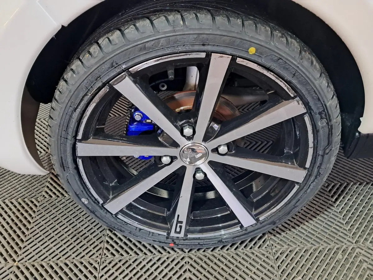 Gros plan sur la roue avant droite de l'AIXAM AMBITION 0.5 CITY COUPE GTI blanche avec jante noire et logo GTI.