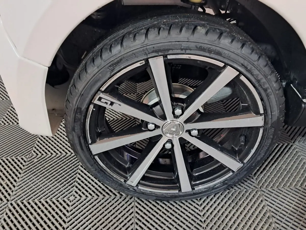 Gros plan sur la roue avant droite noire et argentée avec logo GT d'une Aixam Ambition blanche 2026.