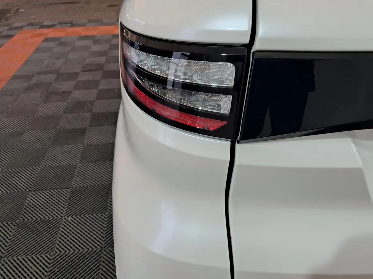 Gros plan sur le feu arrière gauche blanc de l'AIXAM AMBITION 0.5 CITY COUPE GTI 2026 avec bande noire distinctive.