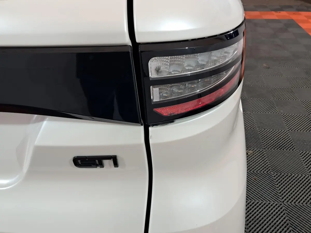 Gros plan sur le feu arrière droit blanc d'une Aixam Ambition 0.5 City Coupe GTI avec logo GTI noir.