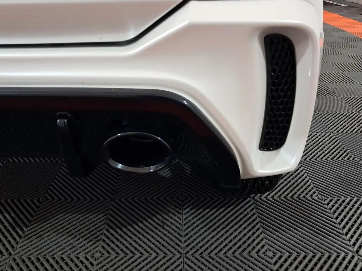 Gros plan sur l'arrière droit blanc de l'AIXAM AMBITION 0.5 CITY COUPE GTI 2026 avec sortie d'échappement et grille noire.