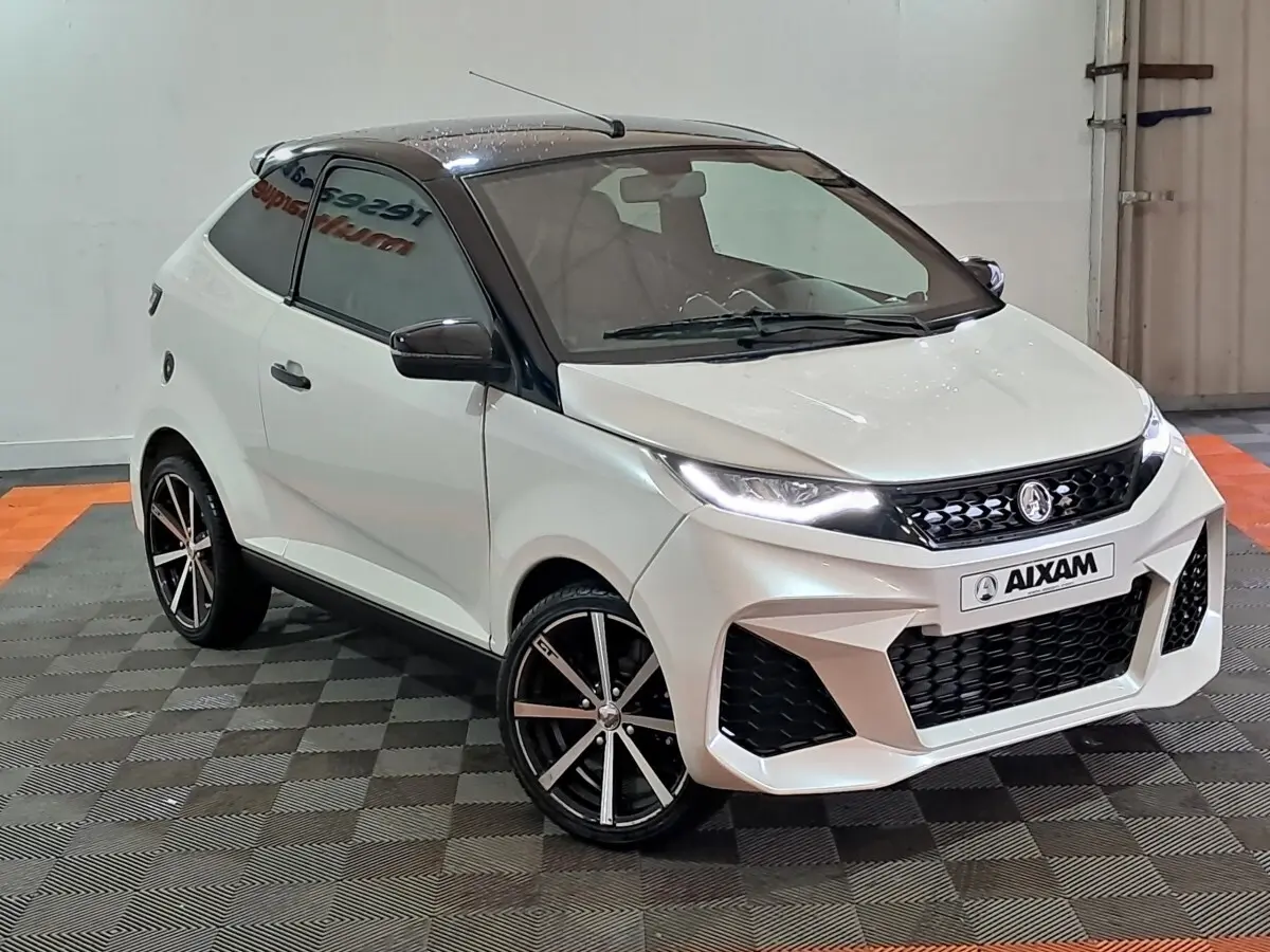 Vue 3/4 avant droite de l'AIXAM AMBITION 0.5 CITY COUPE GTI blanche avec toit noir et jantes sport noires.