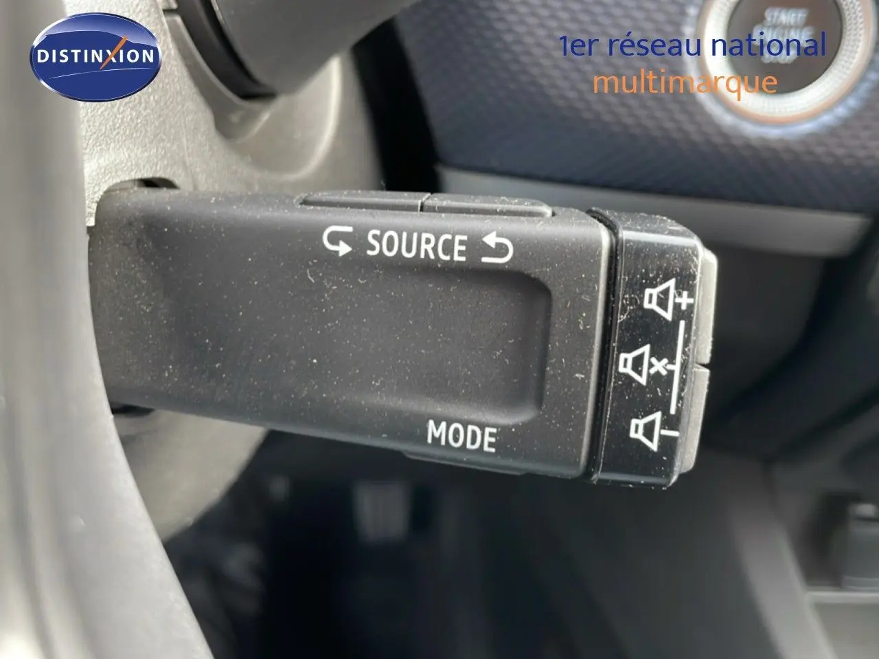 Gros plan sur la commande au volant du Renault Arkana 2024, boutons source et mode visibles sur fond intérieur noir.