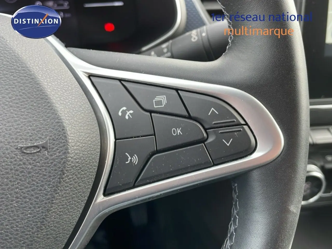 Gros plan sur les commandes au volant en cuir noir du Renault Arkana 2024, version hybride essence, avec boutons multifonctions.