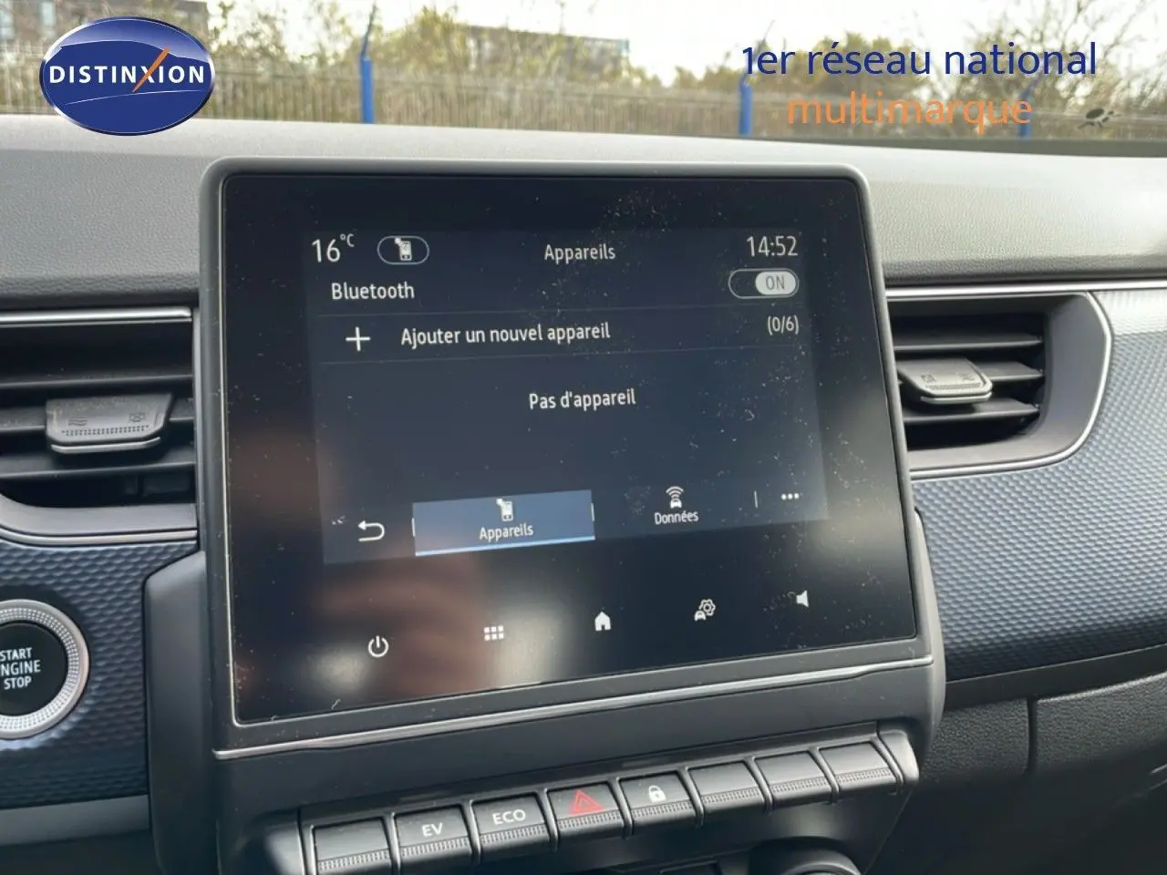 Écran tactile central du tableau de bord de la Renault Arkana 2024, avec interface Bluetooth et boutons de commande en dessous.