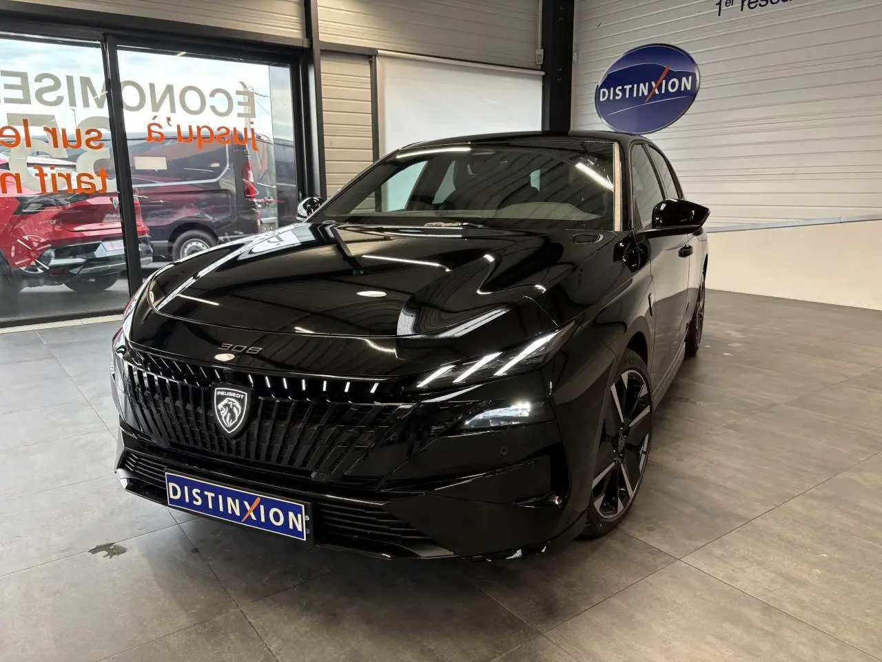 Peugeot 308 noir métallisé vue 3/4 avant droit en intérieur avec calandre noire et jantes alliage bi-ton.