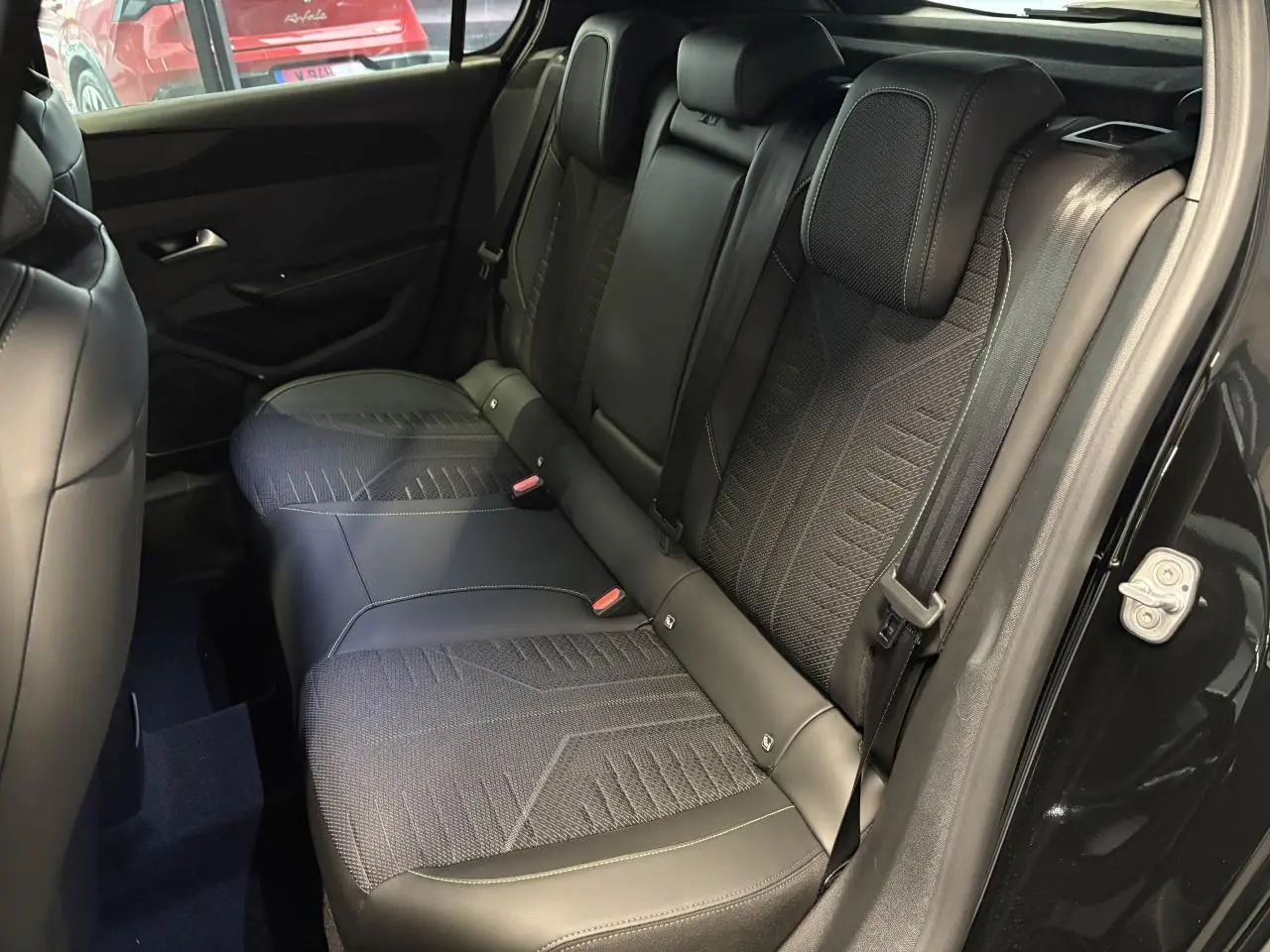 Vue intérieure côté droit montrant la banquette arrière tissu et similicuir noir avec surpiqûres vert Adamite sur Peugeot 308 GT 2026.