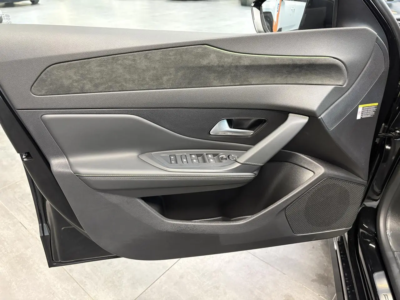 Panneau de porte avant gauche noir avec surpiqûres vert Adamite et commandes électriques sur Peugeot 308 GT 2026.
