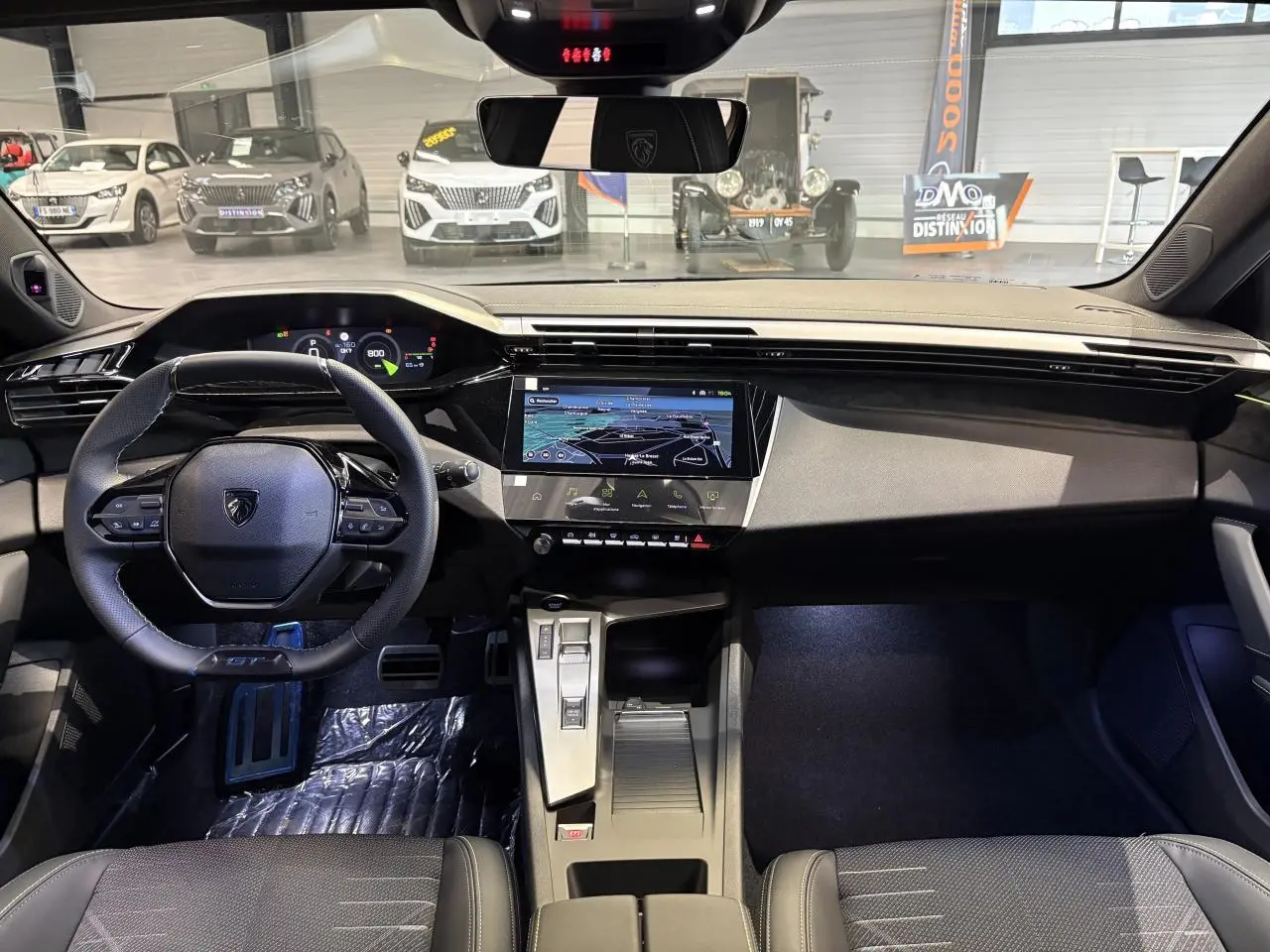 Vue intérieure avant de la Peugeot 308 2026 noire, avec tableau de bord numérique et écran tactile central.