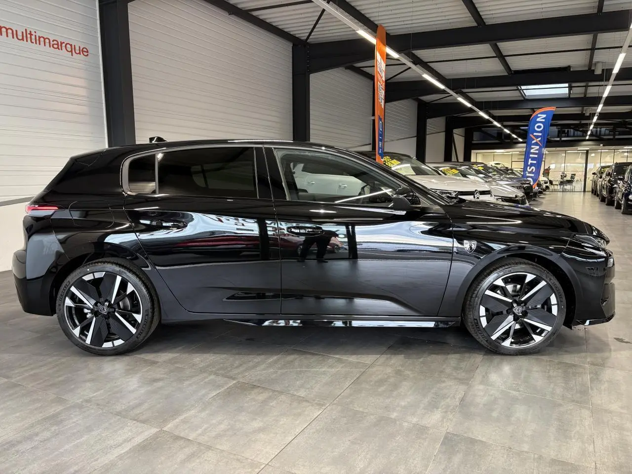 Peugeot 308 noir métallisé vue de profil côté gauche, avec jantes alliage bi-tons et vitres surteintées.