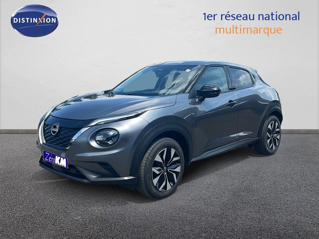 Nissan Juke Hybrid gris squale métal en vue 3/4 avant droit, soulignant ses jantes modernes et son design compact.