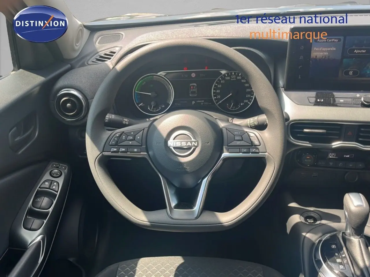 Vue intérieure centrée sur le volant Nissan du Juke Hybrid 2025, avec tableau de bord numérique et console centrale visible.