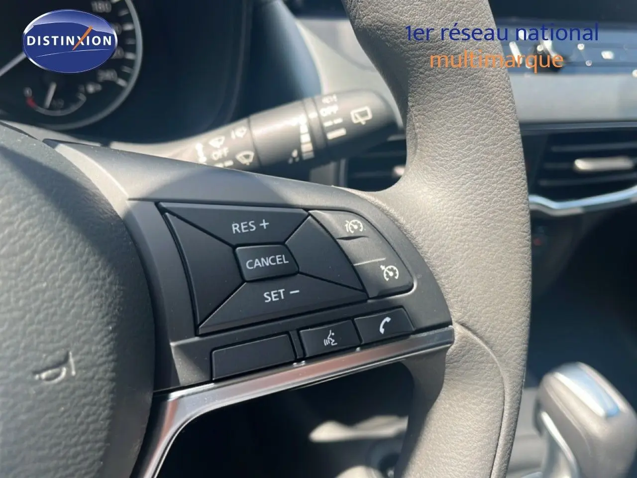 Gros plan sur les commandes à droite du volant gris clair du Nissan Juke Hybrid 2025, avec tableau de bord en arrière-plan.