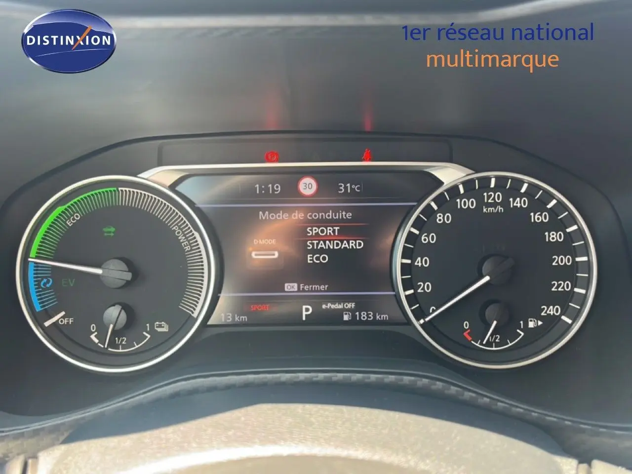 Tableau de bord du Nissan Juke Hybrid 2025 montrant l'affichage numérique des modes de conduite et compteurs analogiques.