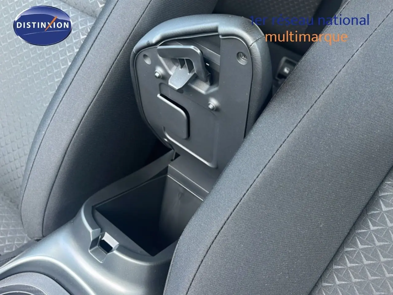 Vue rapprochée de la console centrale ouverte entre les sièges avant du Nissan Juke gris Squale Metal 2025.