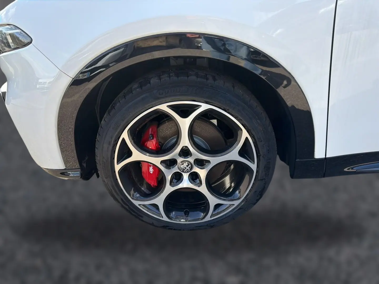Gros plan sur la roue avant gauche blanche d'Alfa Romeo Tonale avec jante alu et étrier de frein rouge.