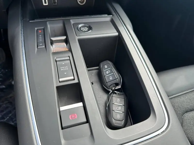 Gros plan sur la console centrale noire du Citroën C5 Aircross 2025 avec clés, bouton start et commandes de boîte automatique.
