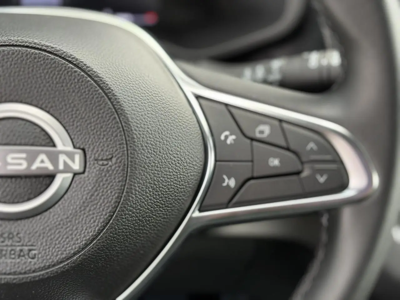 Gros plan sur les commandes multifonctions à droite du volant noir du Nissan Primastar Combi 2025.