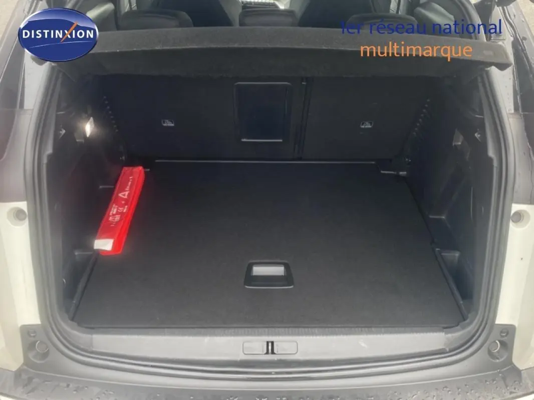 Coffre ouvert vu de l'arrière d'un Peugeot 3008 blanc, montrant un espace de chargement propre avec triangle de signalisation rouge.
