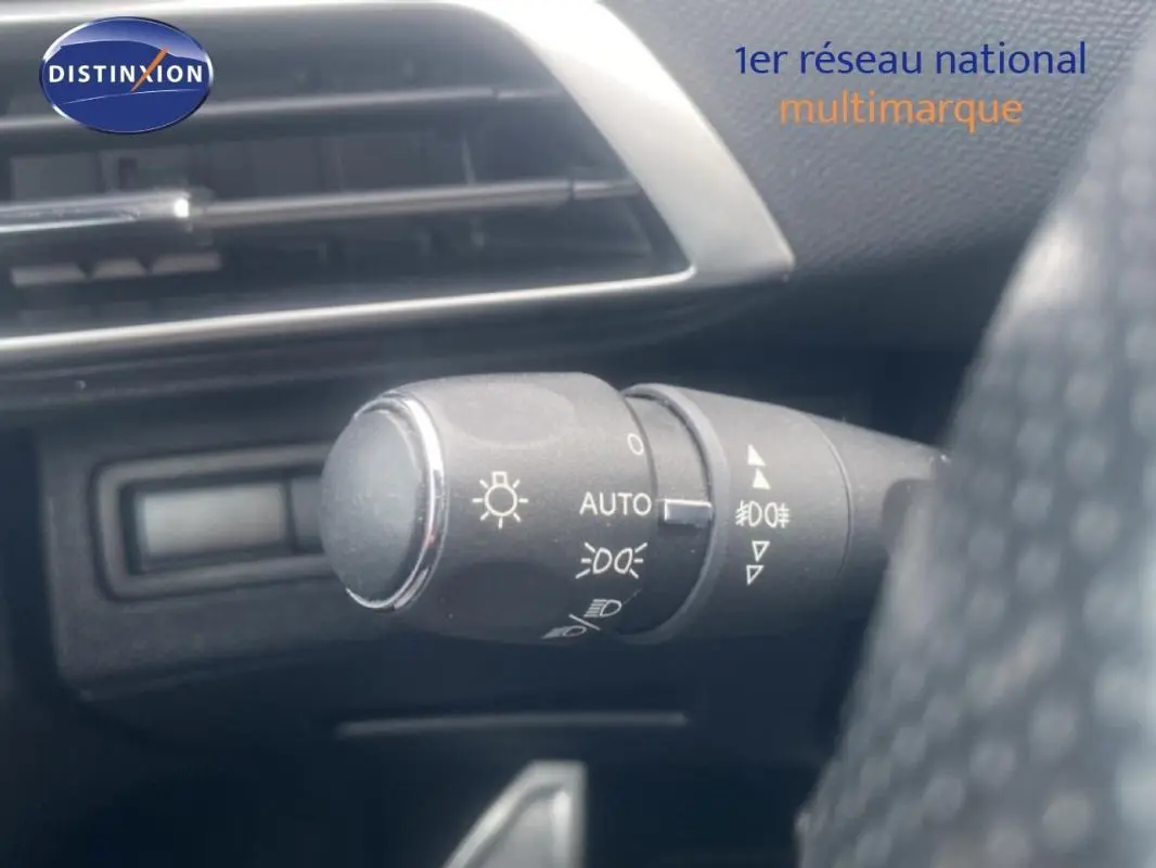 Gros plan sur la commande des phares du Peugeot 3008 blanc, avec tableau de bord et aérateur en arrière-plan.