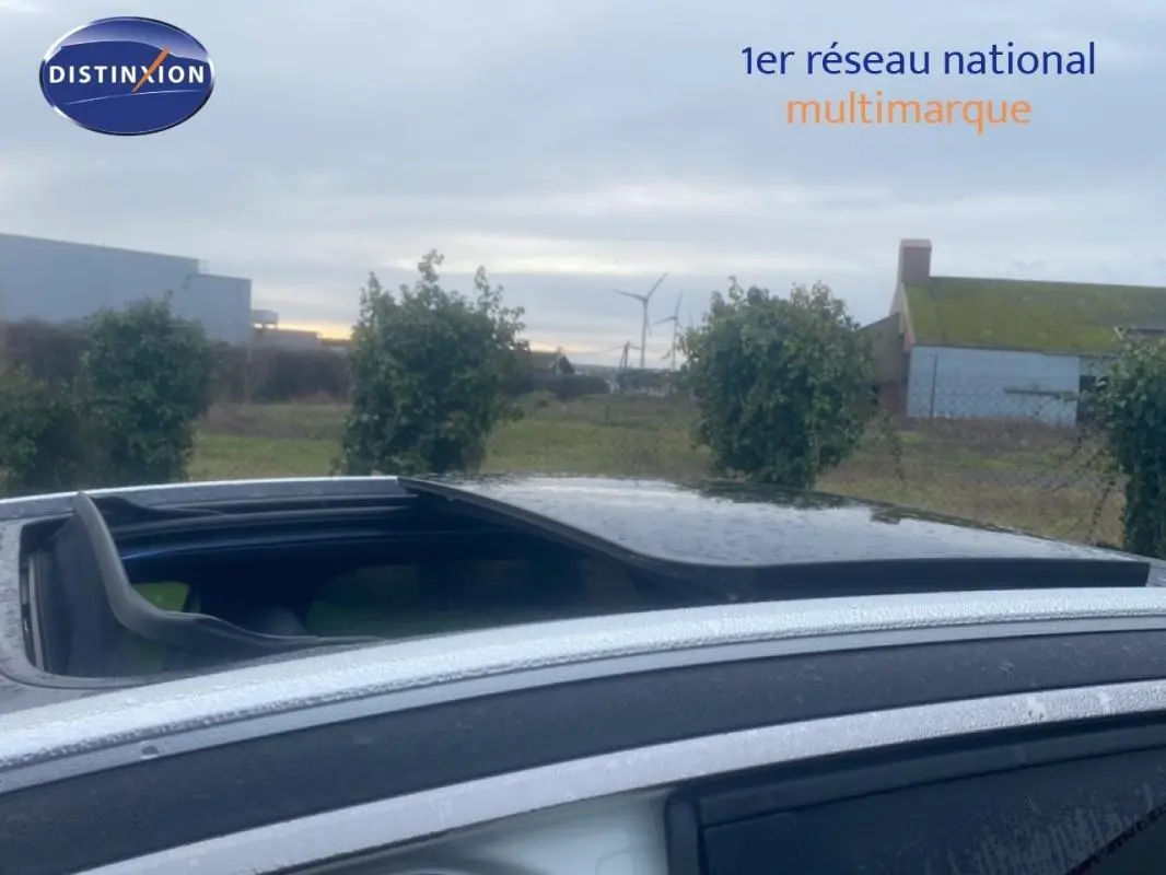 Toit ouvrant panoramique ouvert sur Peugeot 3008 blanc, vue latérale côté gauche sous ciel nuageux.