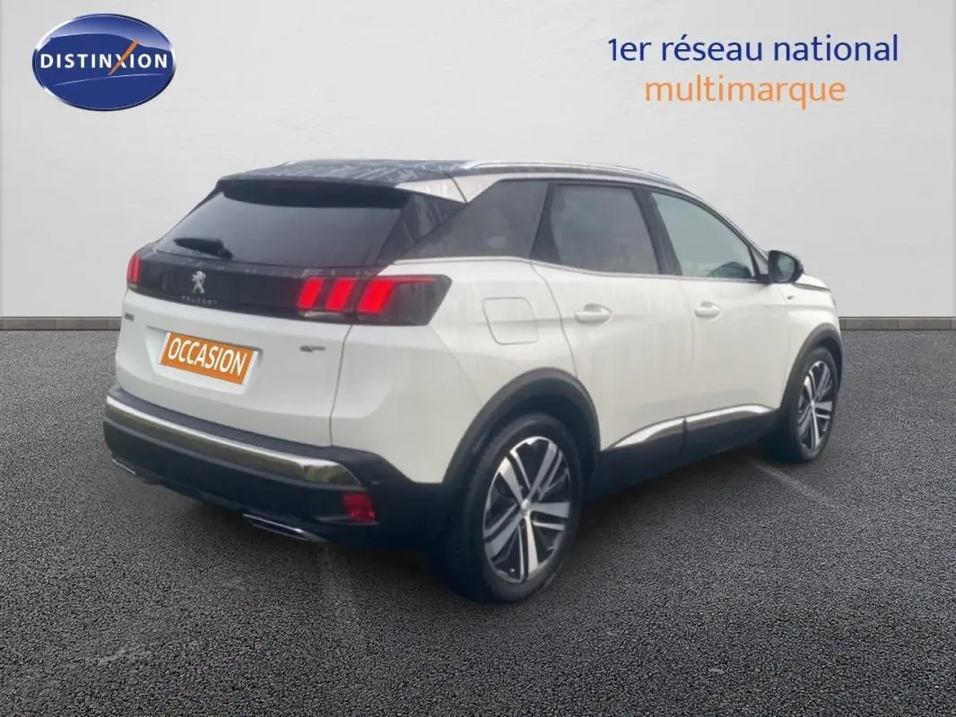 Vue 3/4 arrière droite d’un Peugeot 3008 blanc avec toit noir, jantes alliage 19 pouces et barres de toit.
