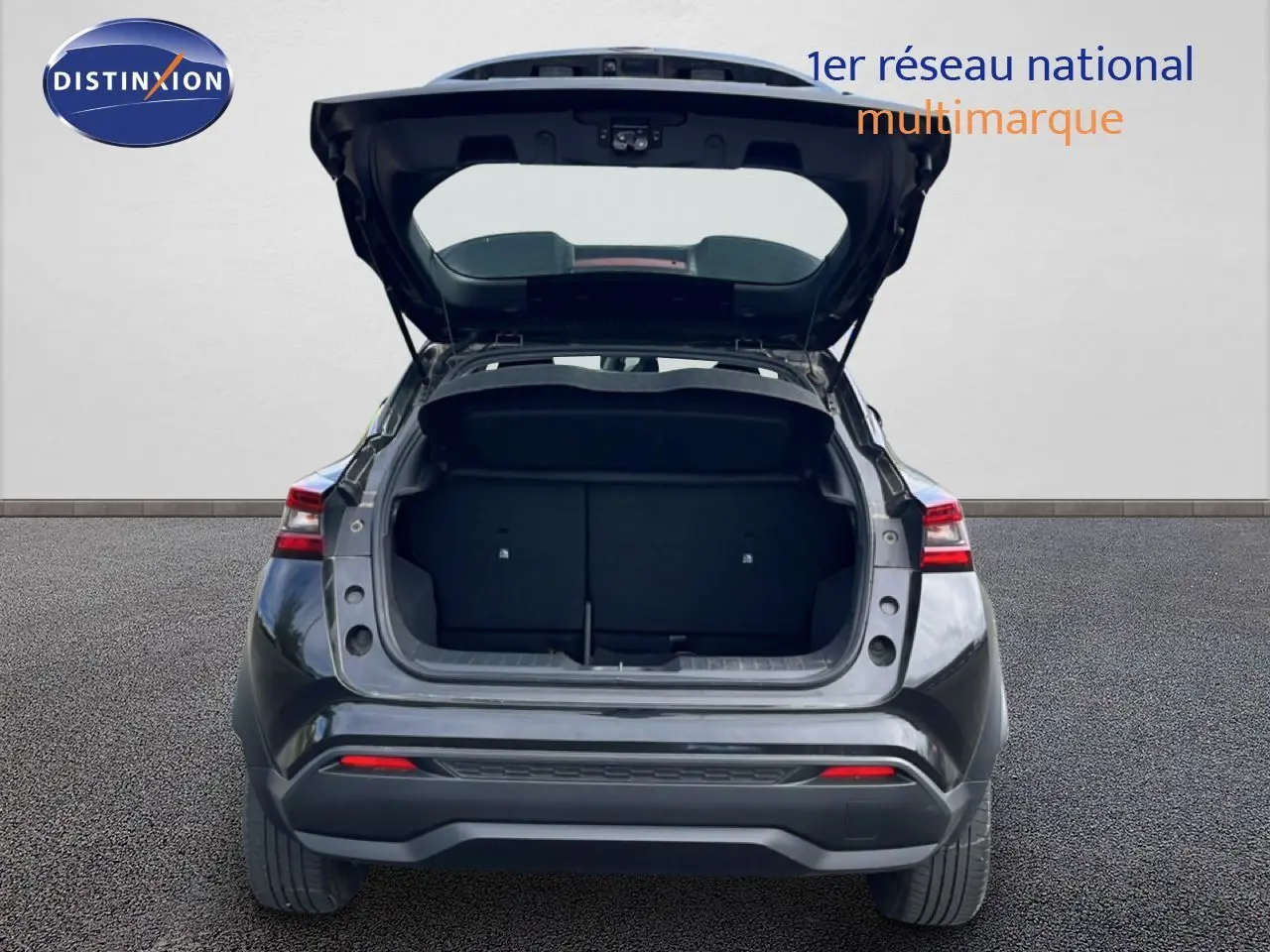 Vue arrière d'un Nissan Juke noir métal 2023 avec coffre ouvert, montrant l'espace de chargement vide.