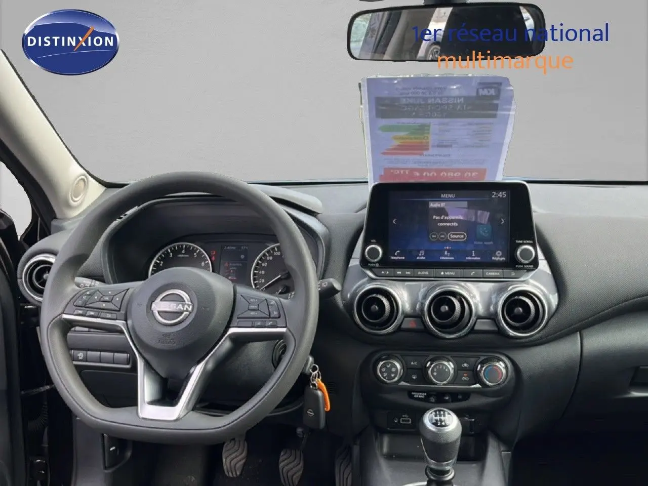 Vue intérieure frontale du tableau de bord noir du Nissan Juke 2023 avec volant multifonction et écran tactile central.