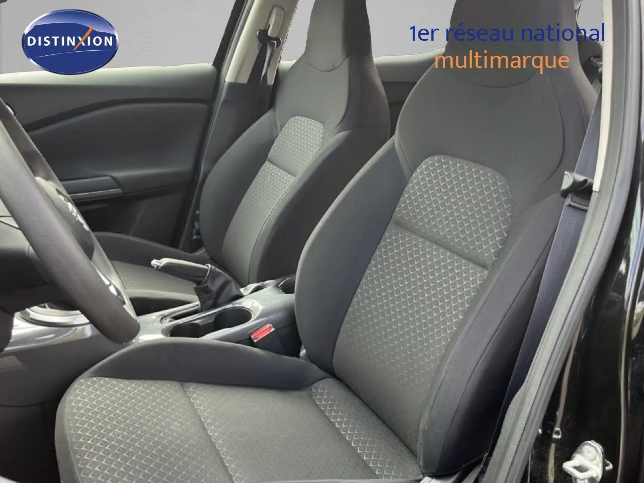 Vue intérieure rapprochée des sièges avant en tissu gris et noir du Nissan Juke 2023 noir métal.