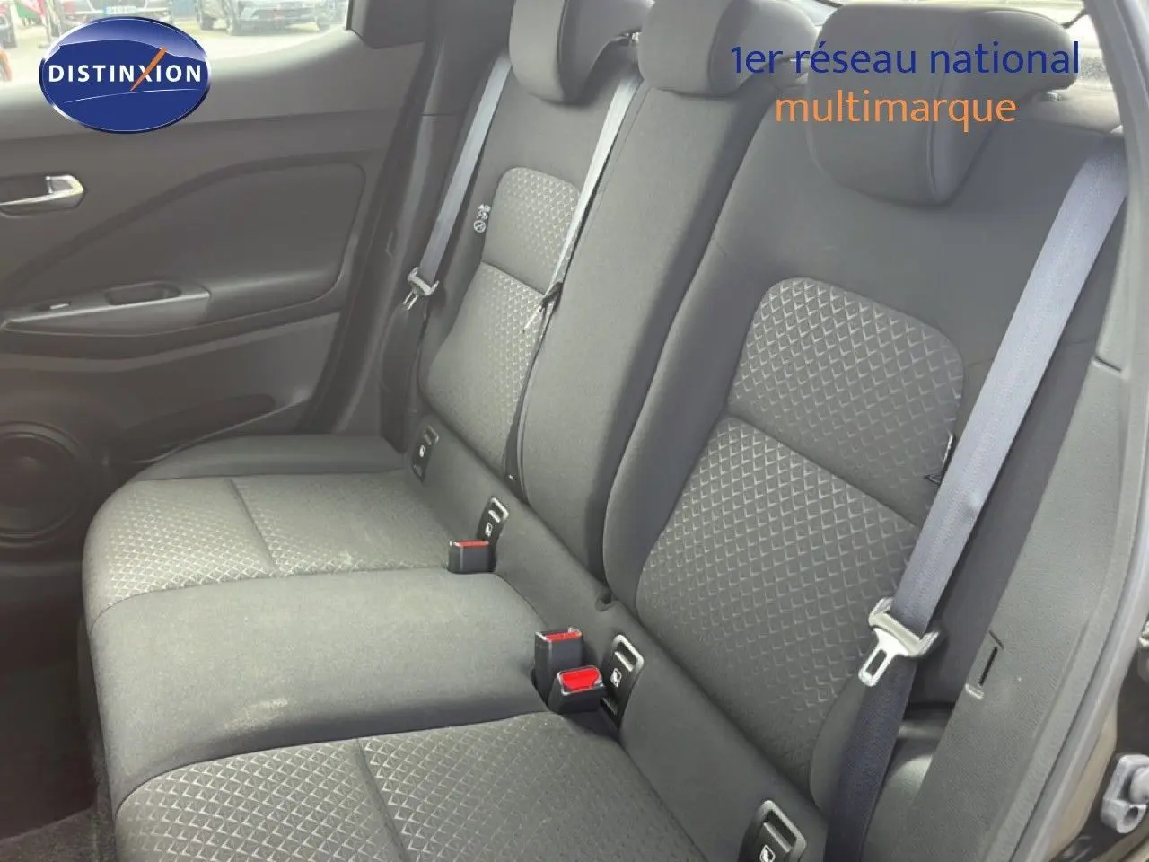 Vue latérale du siège arrière noir tissu du Nissan Juke 2023, mettant en valeur les ceintures de sécurité et les textures du revêtement.