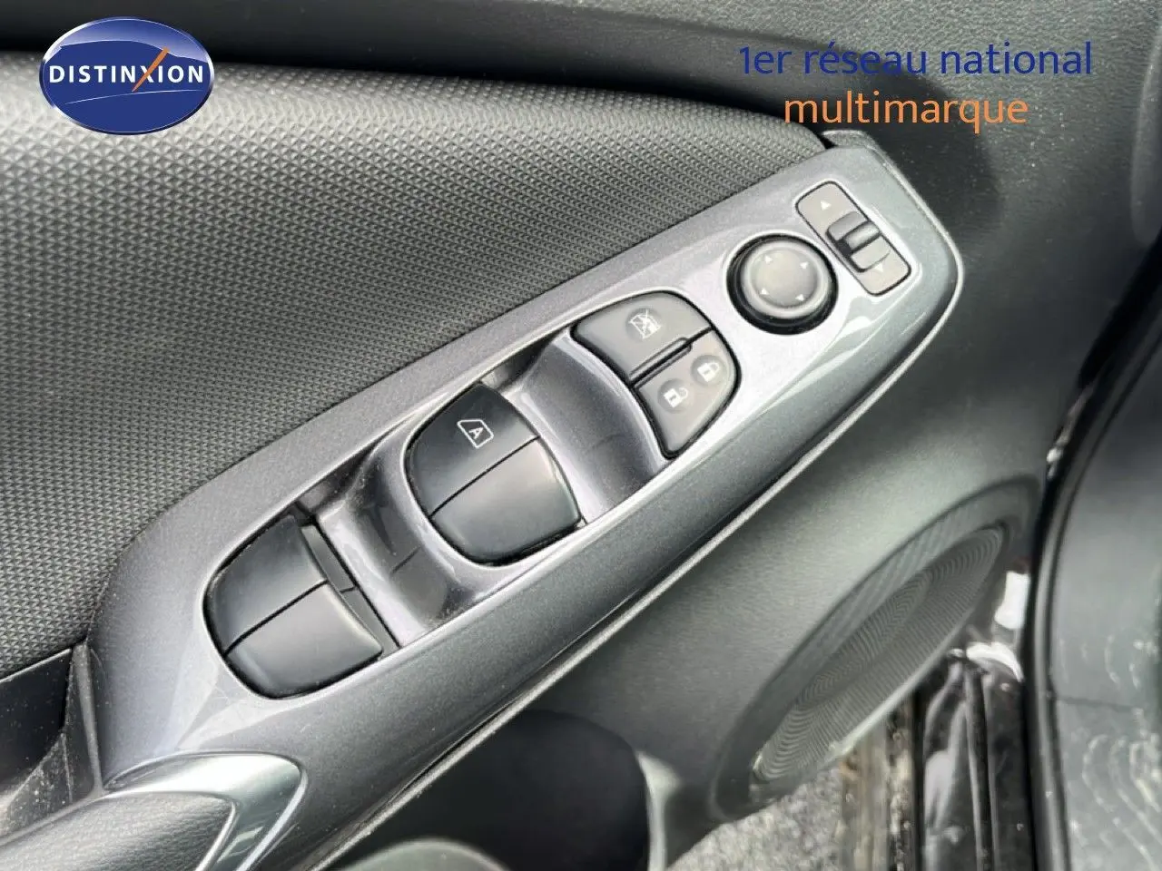 Gros plan sur la commande des vitres et rétroviseurs côté conducteur du Nissan Juke noir métal 2023.