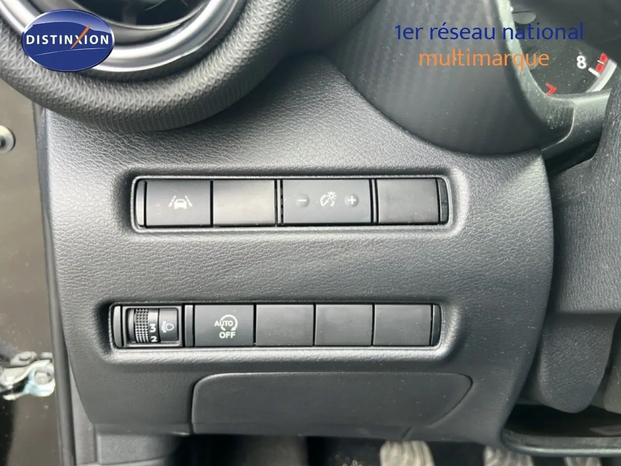 Gros plan sur les commandes de réglage d’éclairage et d’aide à la conduite du tableau de bord d’un Nissan Juke noir métal 2023.