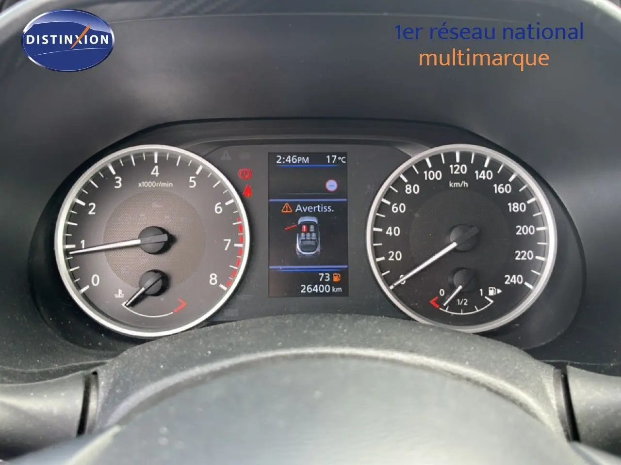 Vue rapprochée du tableau de bord noir du Nissan Juke 2023, avec compte-tours, vitesse et écran central d’alerte.