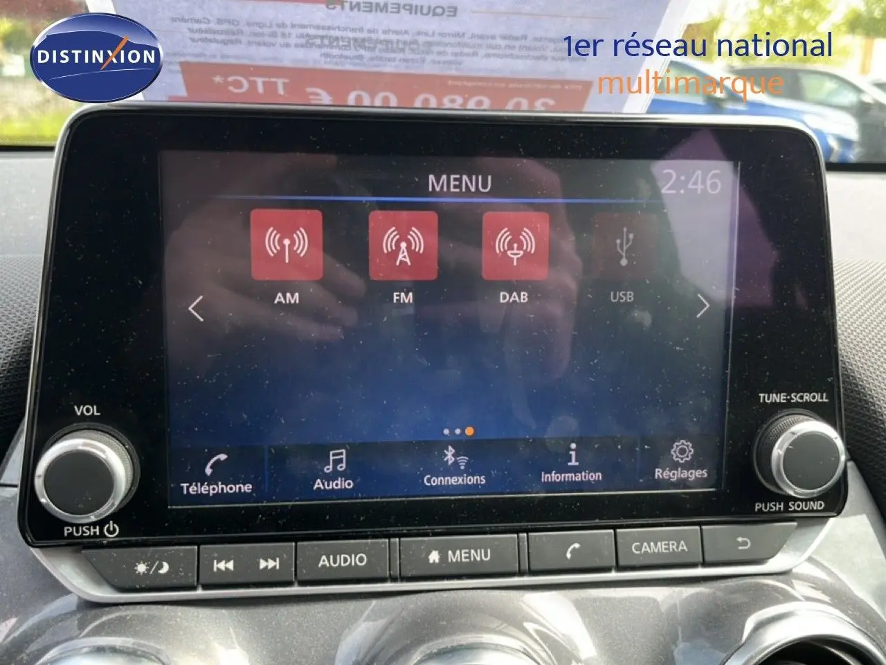 Vue intérieure centrée sur l'écran tactile multimédia du Nissan Juke noir métal 2023 avec commandes audio et caméra.