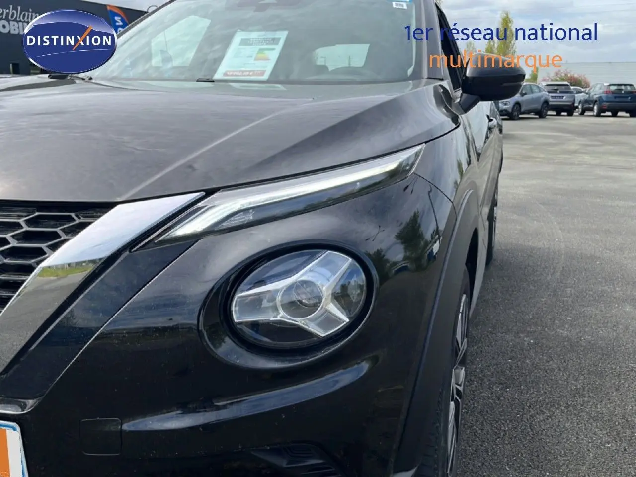 Vue 3/4 avant droit du Nissan Juke noir métal 2023, mettant en valeur ses phares ronds et sa calandre en nid d'abeille.