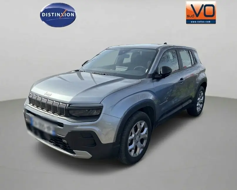 Jeep Avenger gris en 3/4 avant droit, avec calandre noire distinctive et jantes alliage 17 pouces visibles.