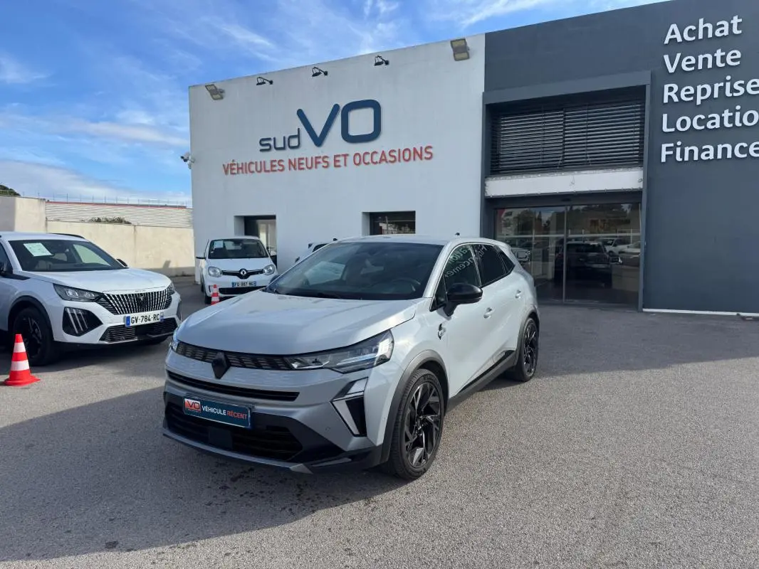 Renault Symbioz gris clair en 3/4 avant droit, avec jantes alliage noires et toit panoramique visible.