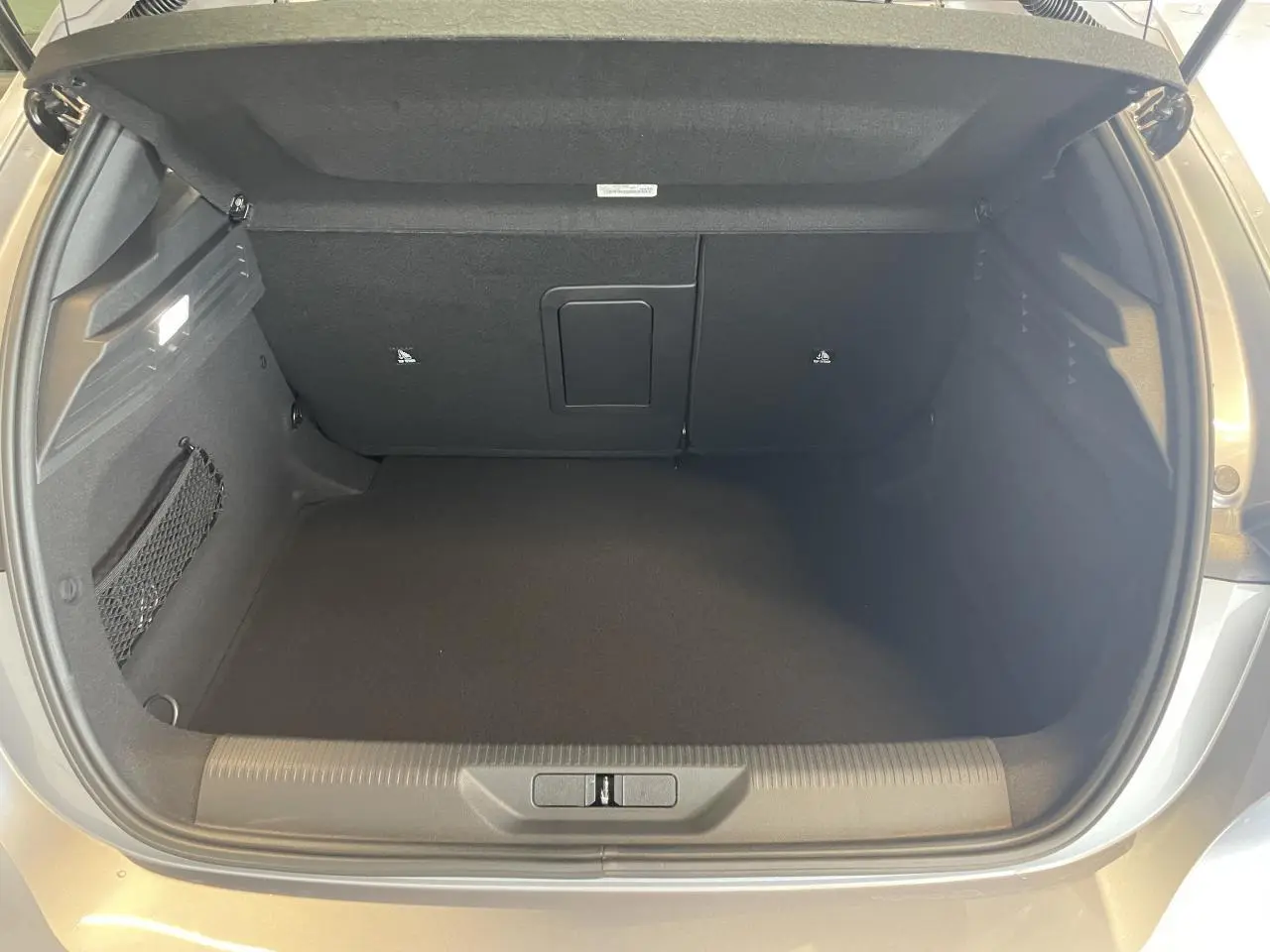 Coffre ouvert vu de l'arrière d'une Peugeot 308 gris Artense, montrant l'espace de chargement vide et les finitions intérieures.