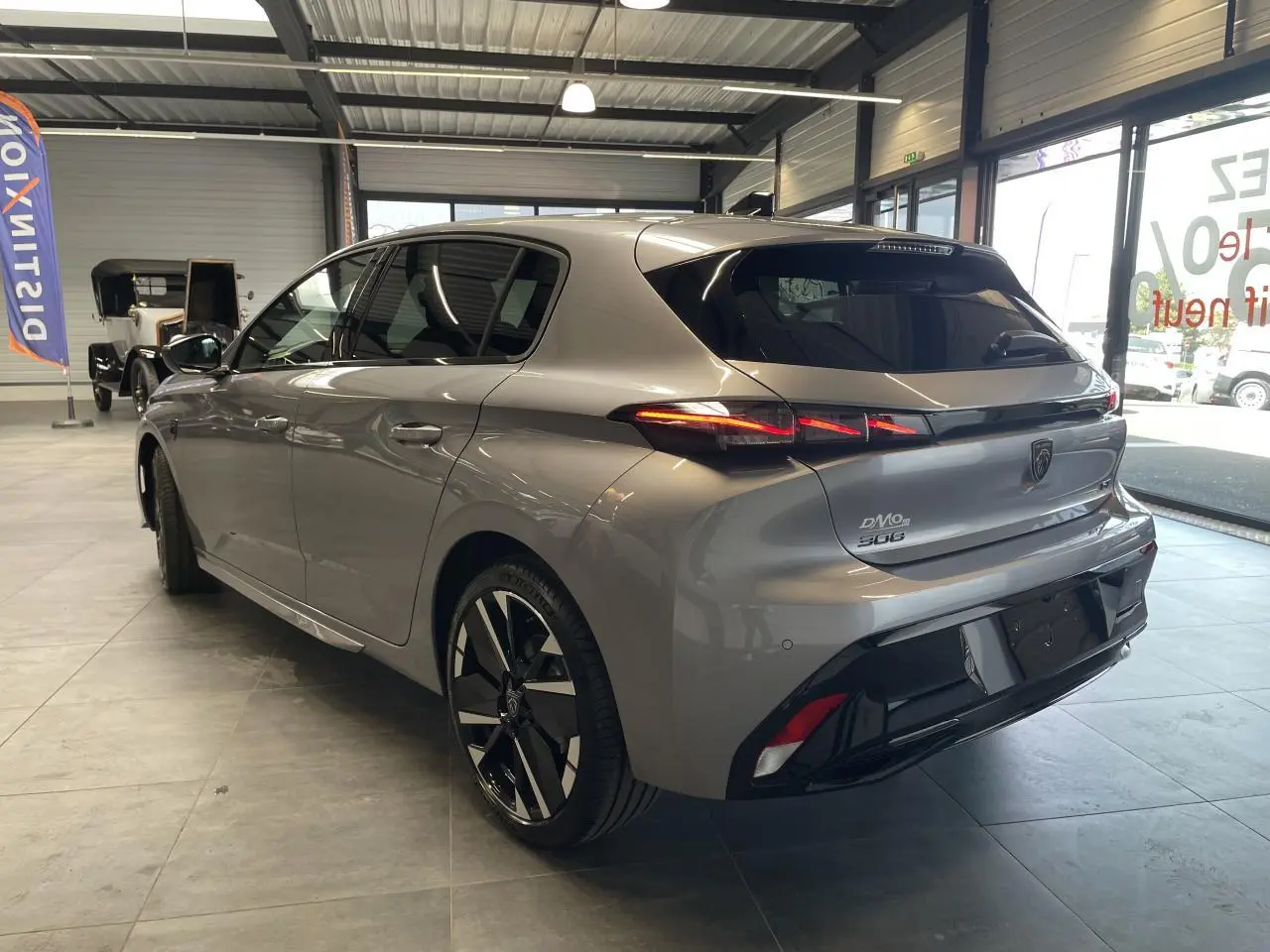 Peugeot 308 gris Artense vue 3/4 arrière droit en intérieur, avec feux arrière LED et jantes alliage bi-tons.