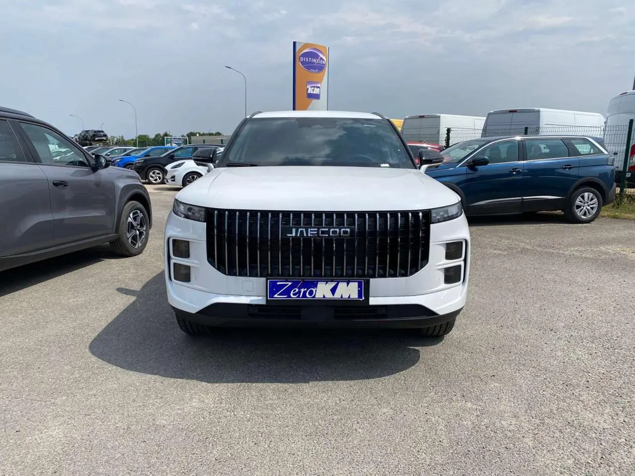 Vue frontale d'un JAECOO J7 blanc khaki avec calandre noire verticale et phares Full LED allumés.
