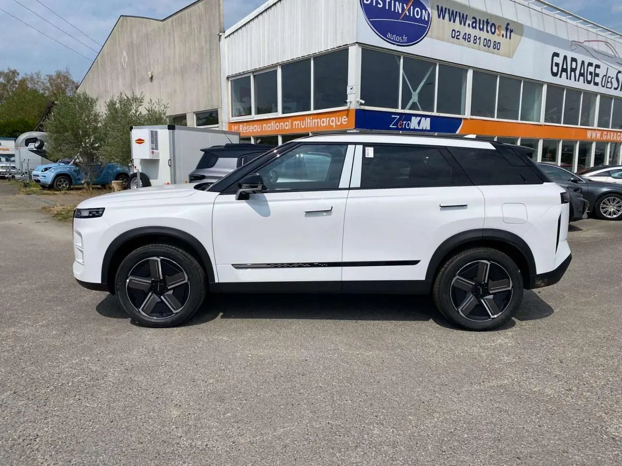 Vue de profil côté gauche du SUV JAECOO J7 blanc khaki avec jantes alliage noires et toit noir contrasté.