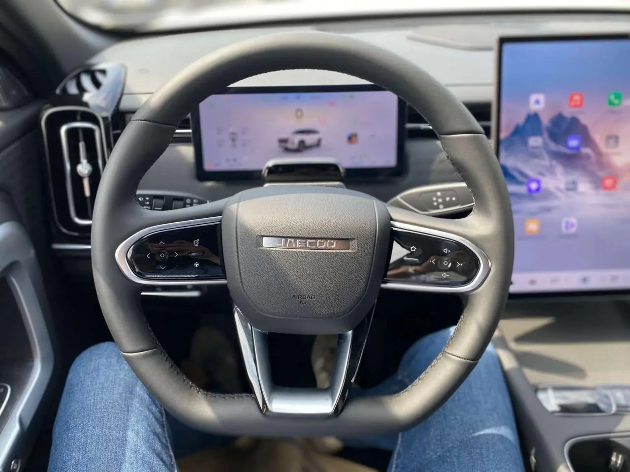 Vue intérieure centrée sur le volant noir du JAECOO J7 2026 avec écrans digitaux en arrière-plan.