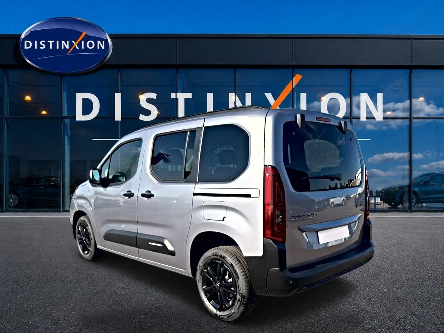 Vue 3/4 arrière droite du Citroën Berlingo Steel Grey 2026 avec jantes alu noires et barres de toit visibles.