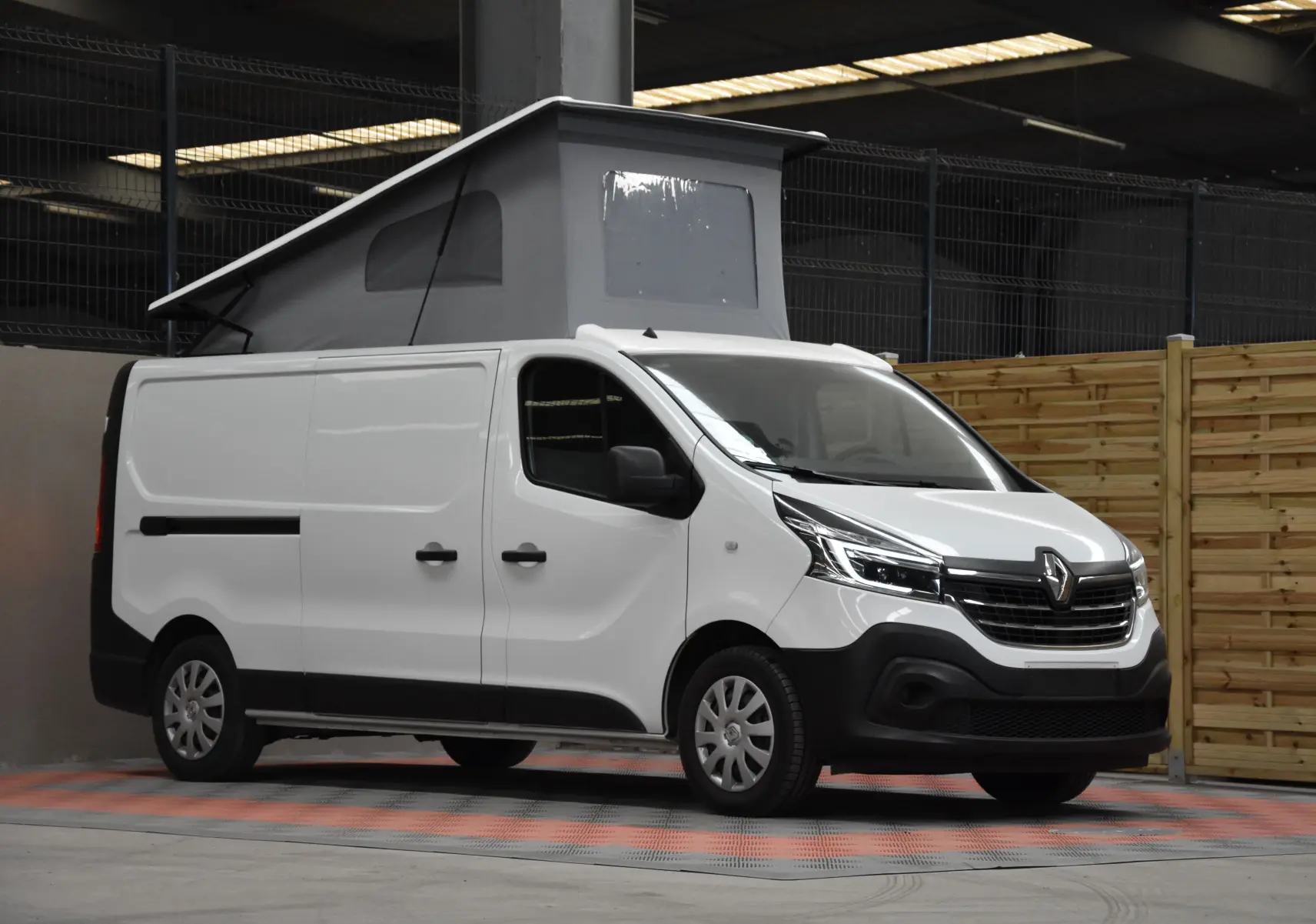 Renault Trafic Combi blanc en 3/4 avant droit avec toit relevé et carrosserie utilitaire visible en intérieur.