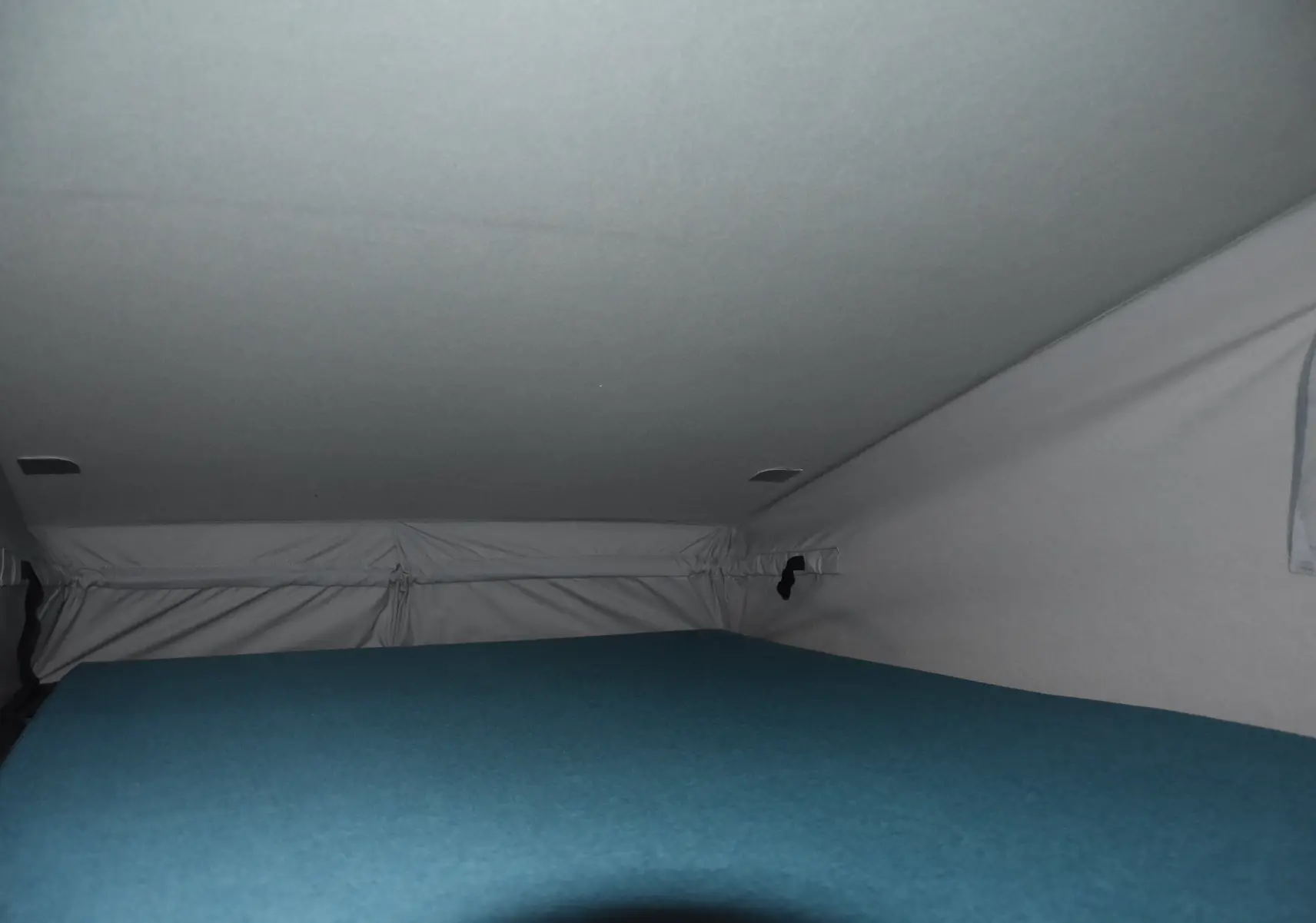 Vue intérieure du toit relevable avec couchage bleu dans un Renault Trafic Combi blanc 2021