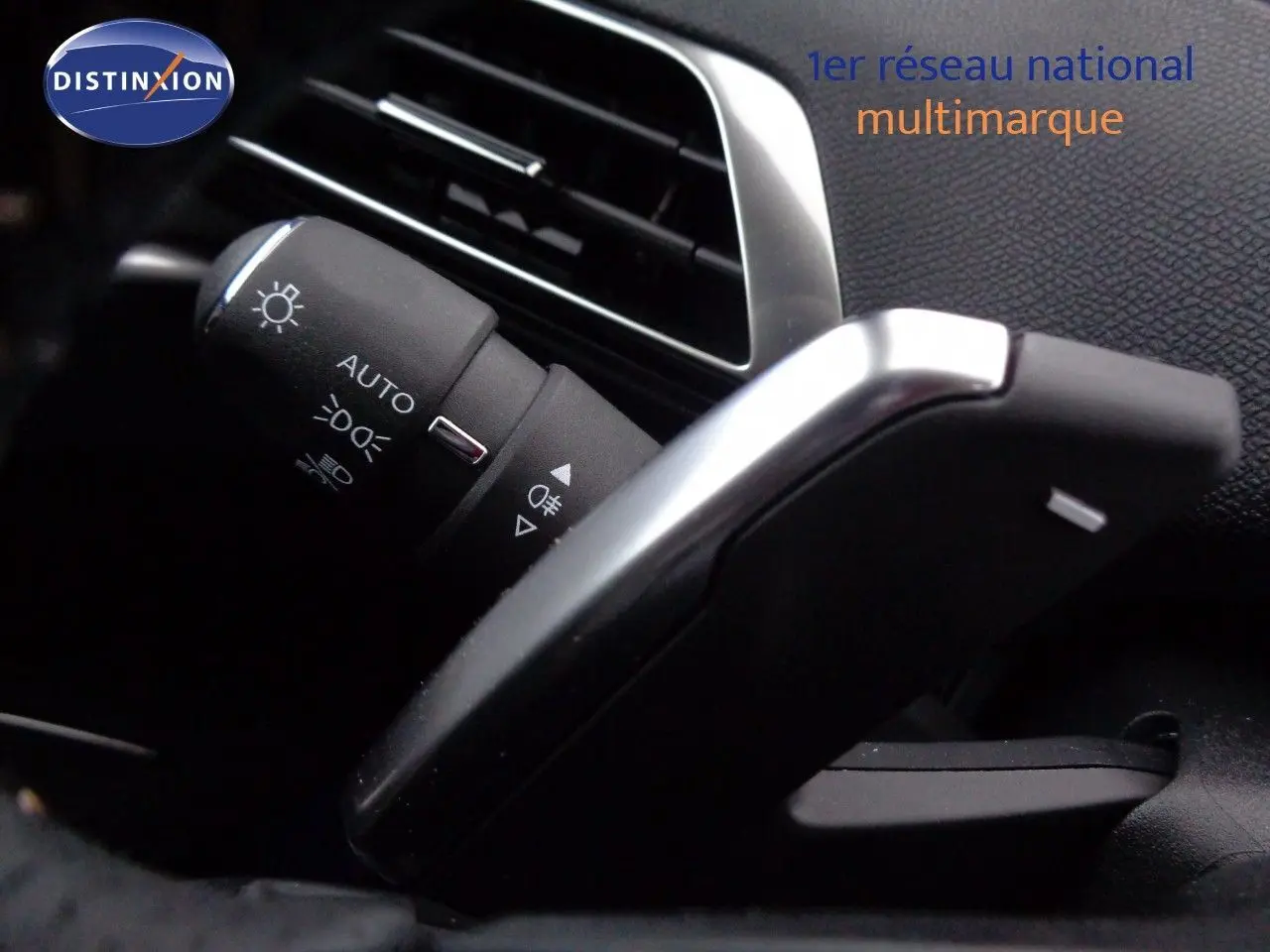 Gros plan sur la commande des phares et clignotants à gauche du volant dans l'habitacle noir du Peugeot 3008 gris Artense.