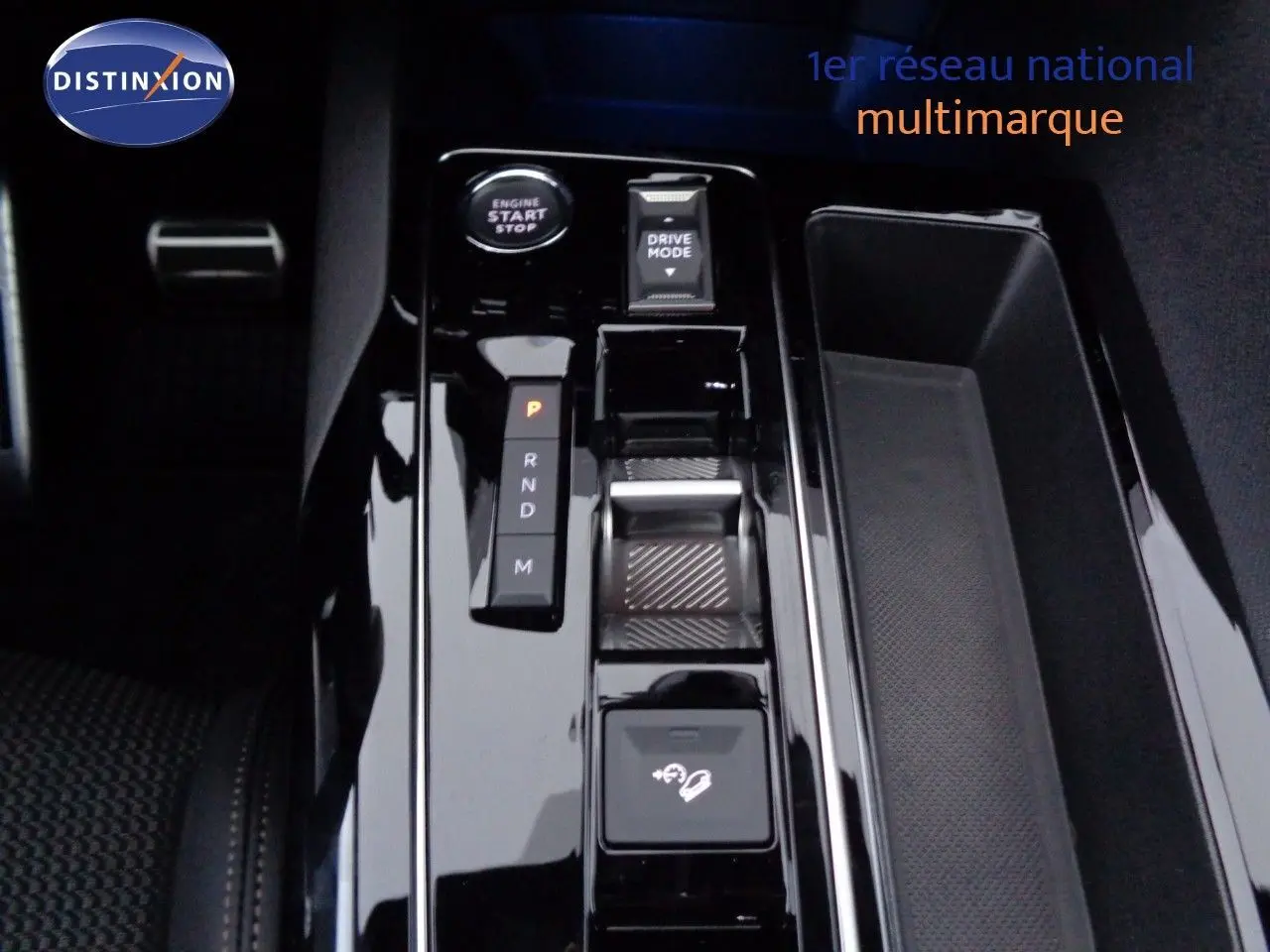 Gros plan sur la console centrale noire brillante du Peugeot 3008 2023 avec bouton start, levier de vitesses et commandes de conduite.