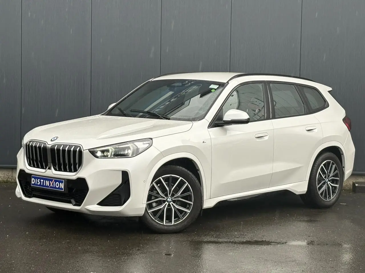 BMW X1 sDrive 20d blanc Mineral vue 3/4 avant droit avec calandre imposante et jantes bicolores 18 pouces.