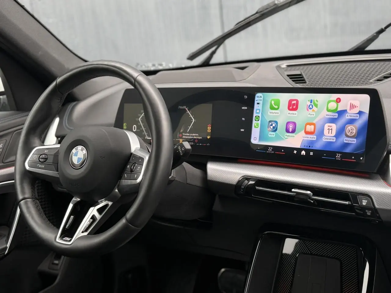 Vue intérieure du tableau de bord et volant cuir noir du BMW X1 sDrive 20d 2025 avec écran tactile incurvé.