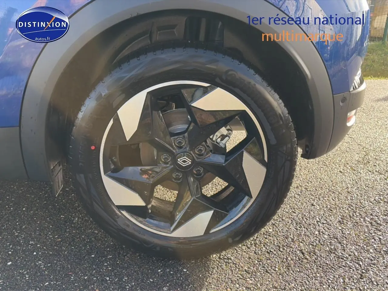 Gros plan sur la roue avant droite du Renault Captur bleu iron avec jante alu bicolore au design moderne.